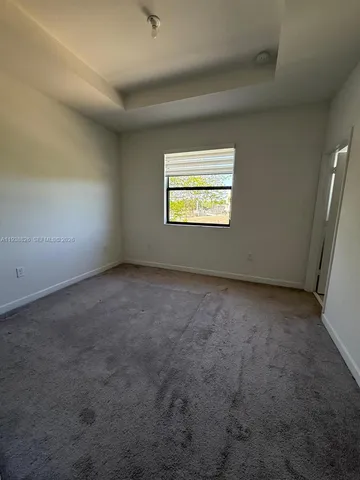 an empty room with windows and wall fan