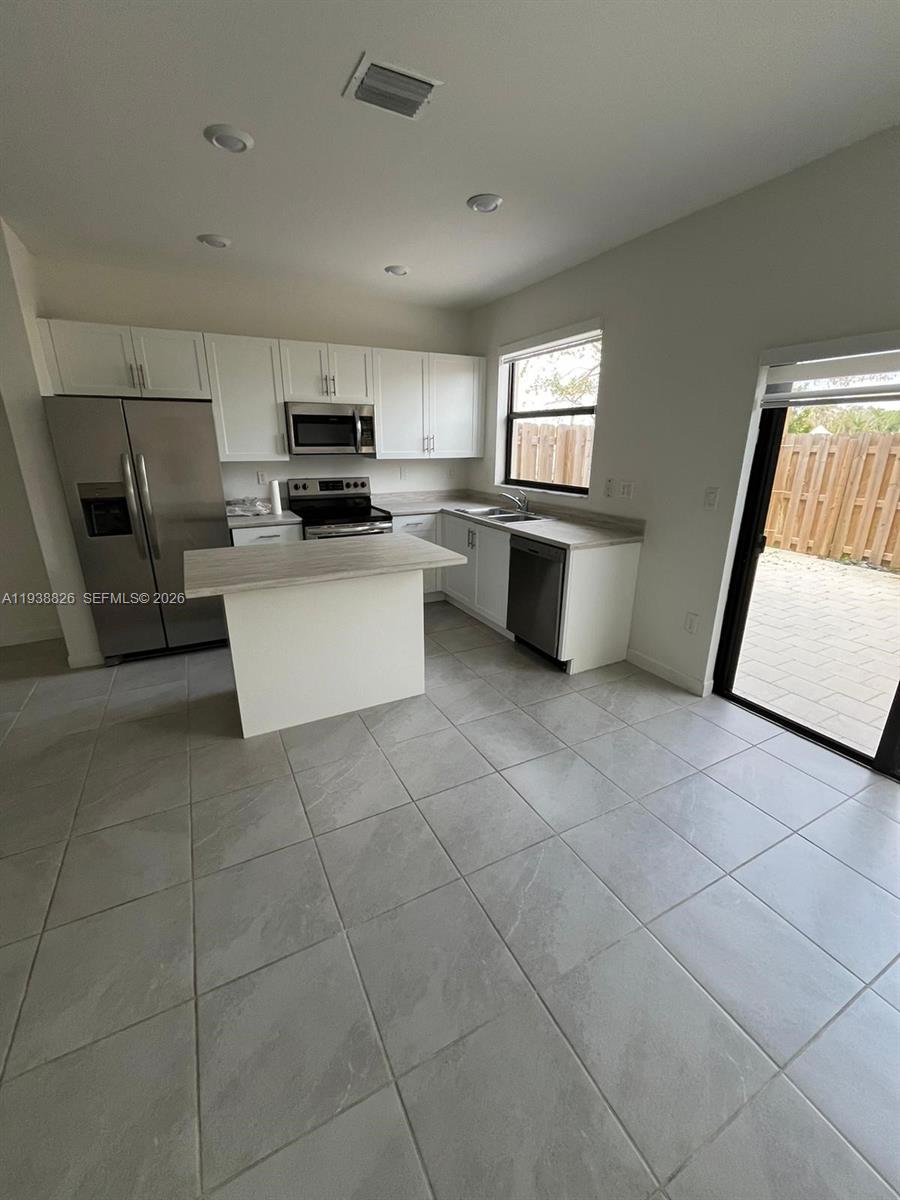 9941 Southwest 228th Terrace, Unit 9941 Miami, FL 33190 - Photo 3 of 31 a kitchen with a sink a counter top space and appliances
