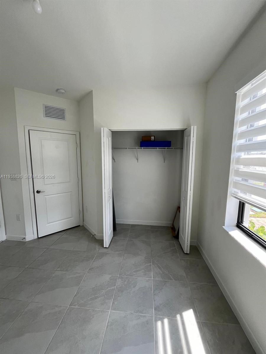 9941 Southwest 228th Terrace, Unit 9941 Miami, FL 33190 - Photo 6 of 31 an empty room with windows and closet