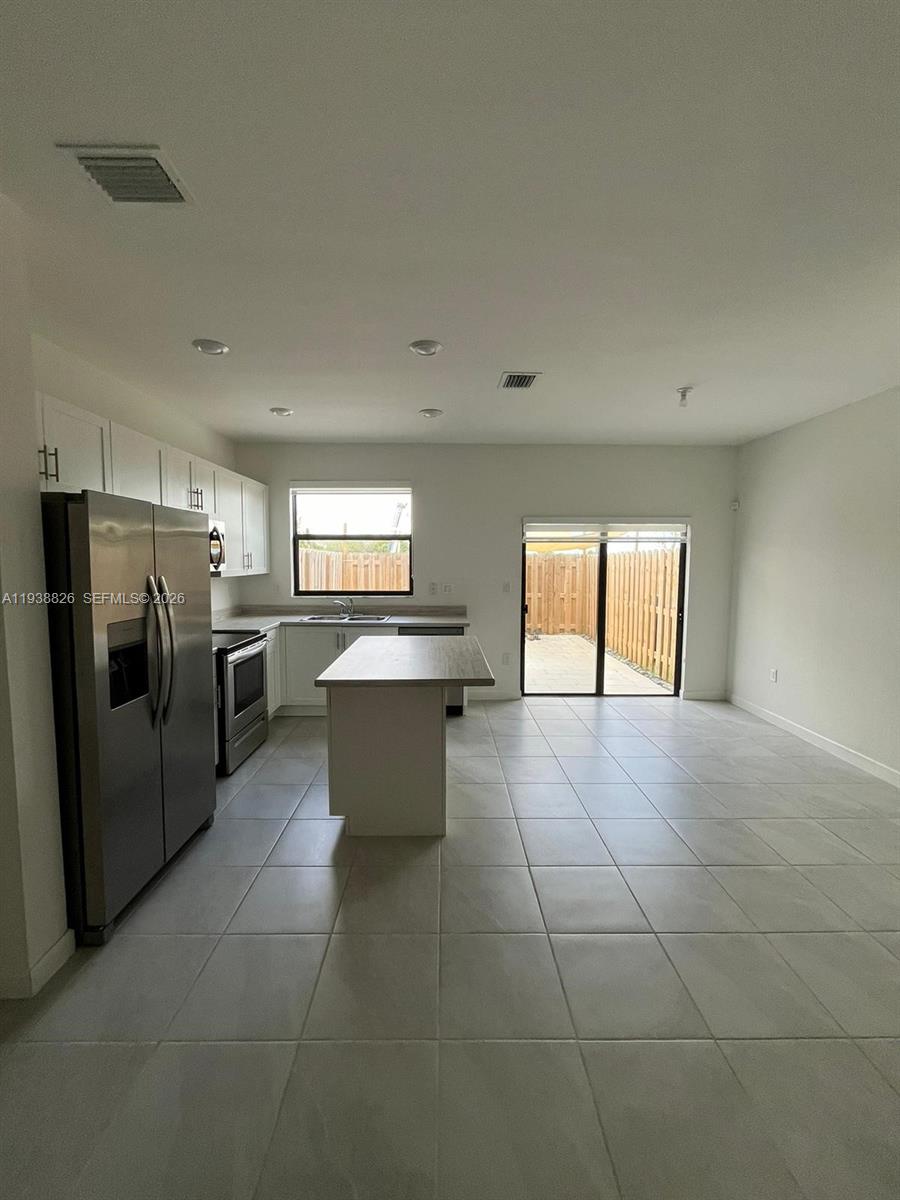 9941 Southwest 228th Terrace, Unit 9941 Miami, FL 33190 - Photo 9 of 31 a large kitchen with a stove a refrigerator and a sink