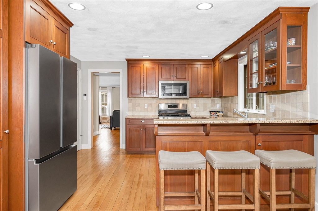 4 Coleman Road Newbury, MA 01922 - Photo 11 of 42 a kitchen with stainless steel appliances granite countertop a refrigerator a sink dishwasher a stove and a microwave oven with wooden floor