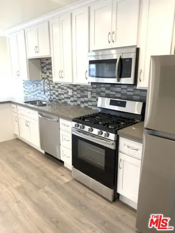 a kitchen with stainless steel appliances white cabinets a stove a sink and a microwave