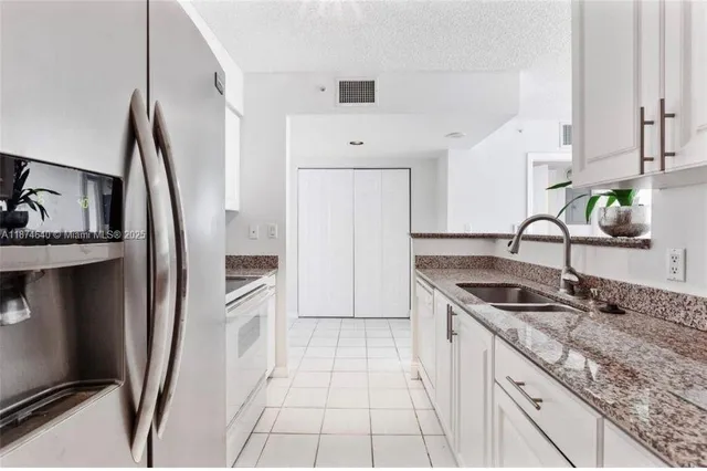 a kitchen with granite countertop a sink stove and refrigerator