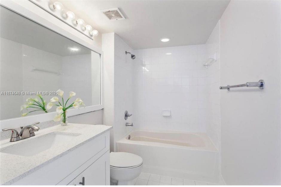 1155 Brickell Bay Drive, Unit 1705 Miami, FL 33131 - Photo 6 of 8 a bathroom with a granite countertop sink a toilet a mirror and shower