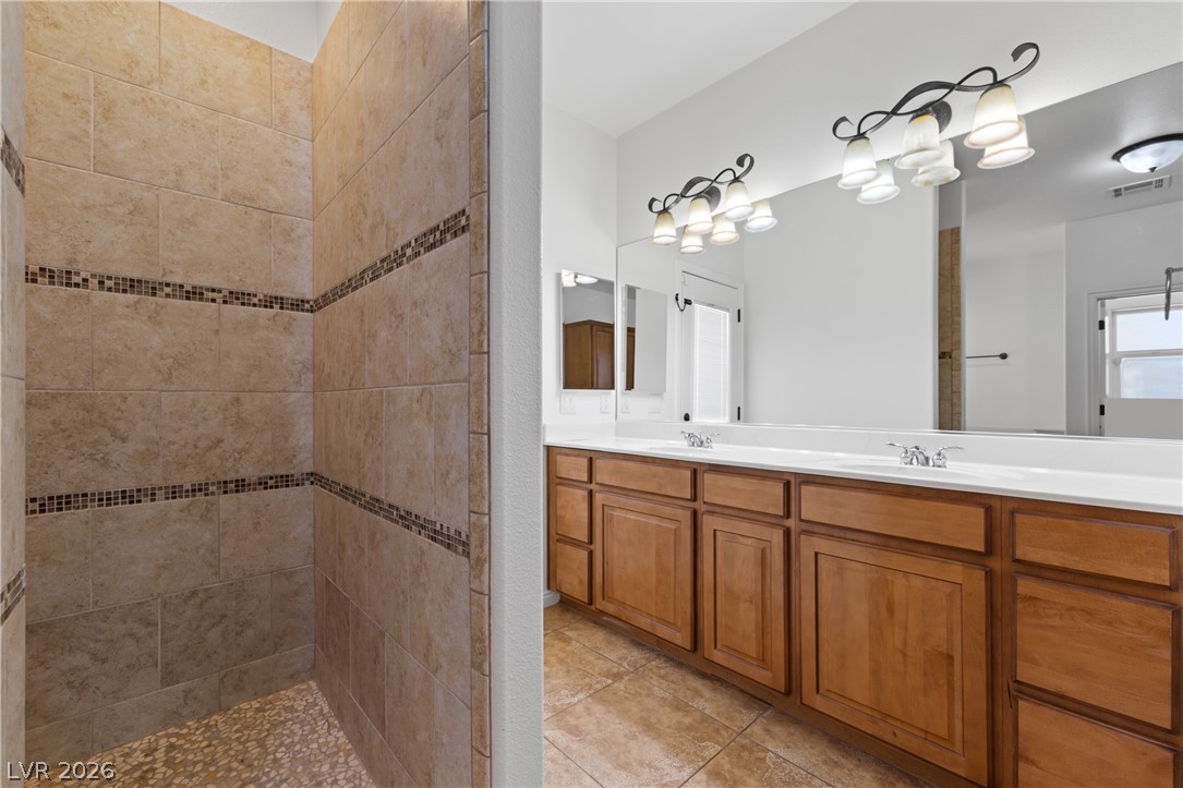 575 Gann Avenue Logandale, NV 89021 - Photo 34 of 75 A well-appointed primary bathroom featuring a tiled walk-in shower and a double vanity.