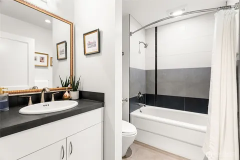 a bathroom with a granite countertop sink mirror toilet and bathtub