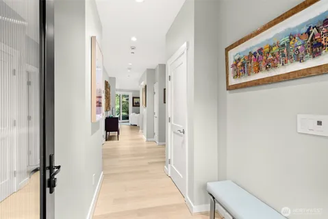 a view of a hallway to a livingroom with wooden floor and furniture