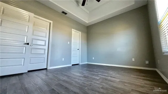 an empty room with wooden floor cabinet and windows
