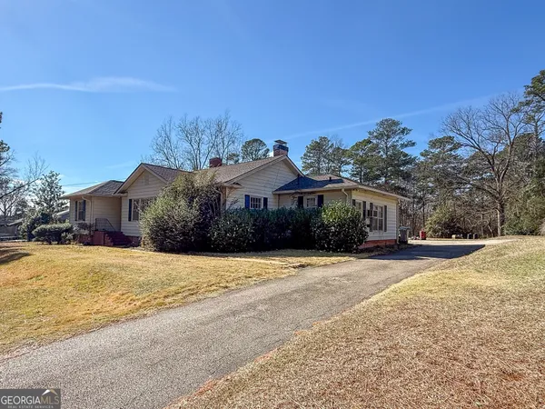 a front view of a house with a yard covered with trees