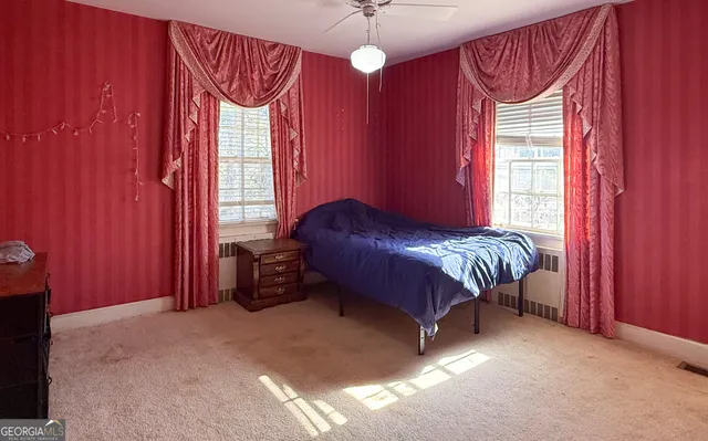 a bed sitting in a bedroom next to a window and a chandelier
