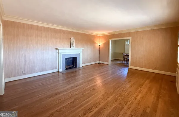 an empty room with wooden floor a fireplace and windows