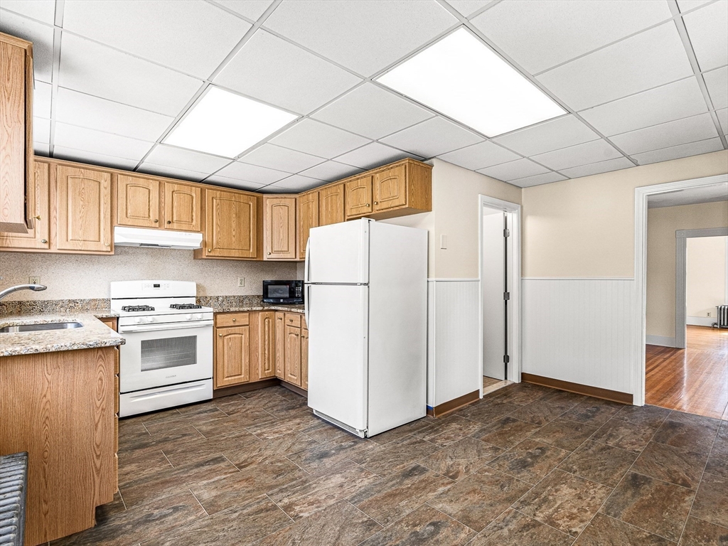 16 Porter Street, Unit 2 Somerville, MA 02143 - Photo 4 of 26 a kitchen with granite countertop white cabinets and white appliances