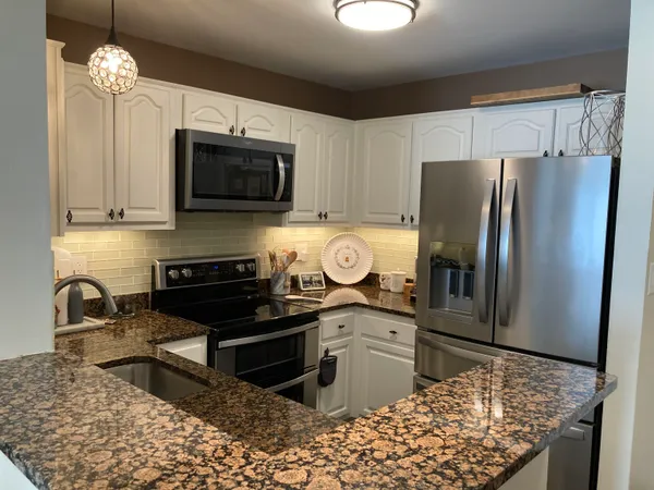 a kitchen with stainless steel appliances granite countertop a sink a stove and a microwave