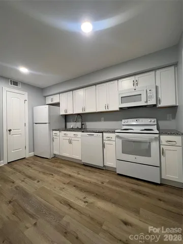 a kitchen with white cabinets and white appliances