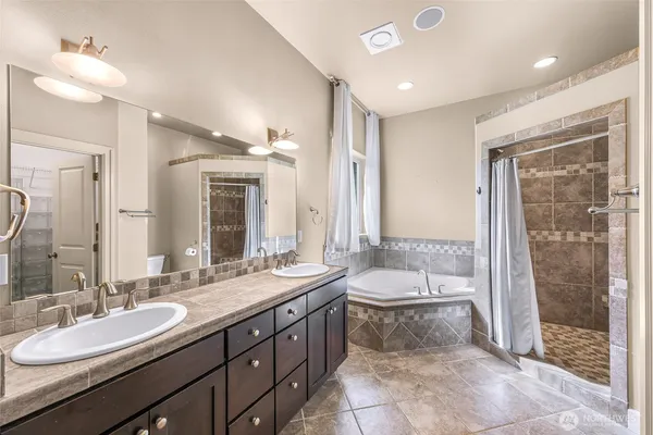 a bathroom with a double vanity sink large mirror and shower
