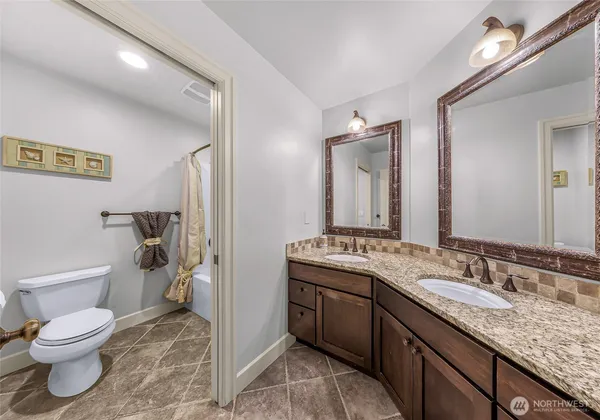 a bathroom with a granite countertop toilet sink and mirror