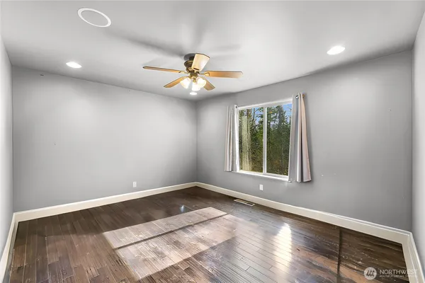 an empty room with windows and ceiling fan