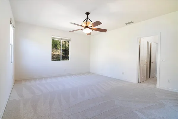 an empty room with windows and fan