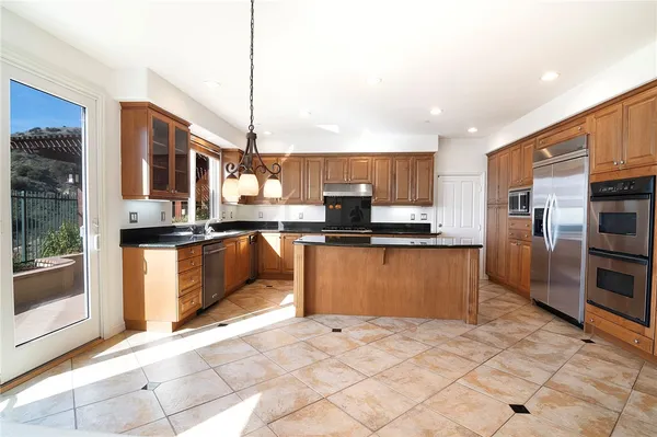 a kitchen with stainless steel appliances granite countertop a refrigerator a sink a stove top oven and cabinets