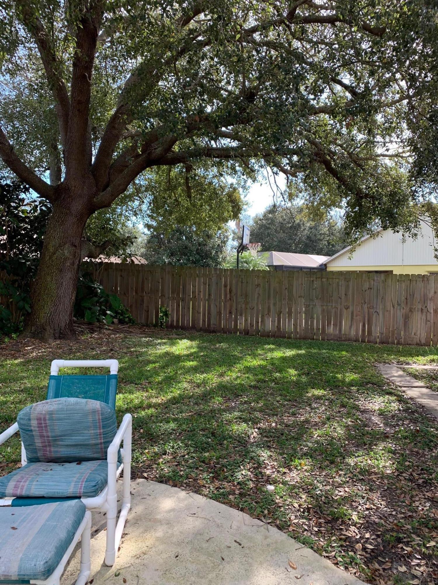 3358 Lakeview Circle Melbourne, FL 32934 - Photo 14 of 14 a view of a backyard with wooden fence and a large tree