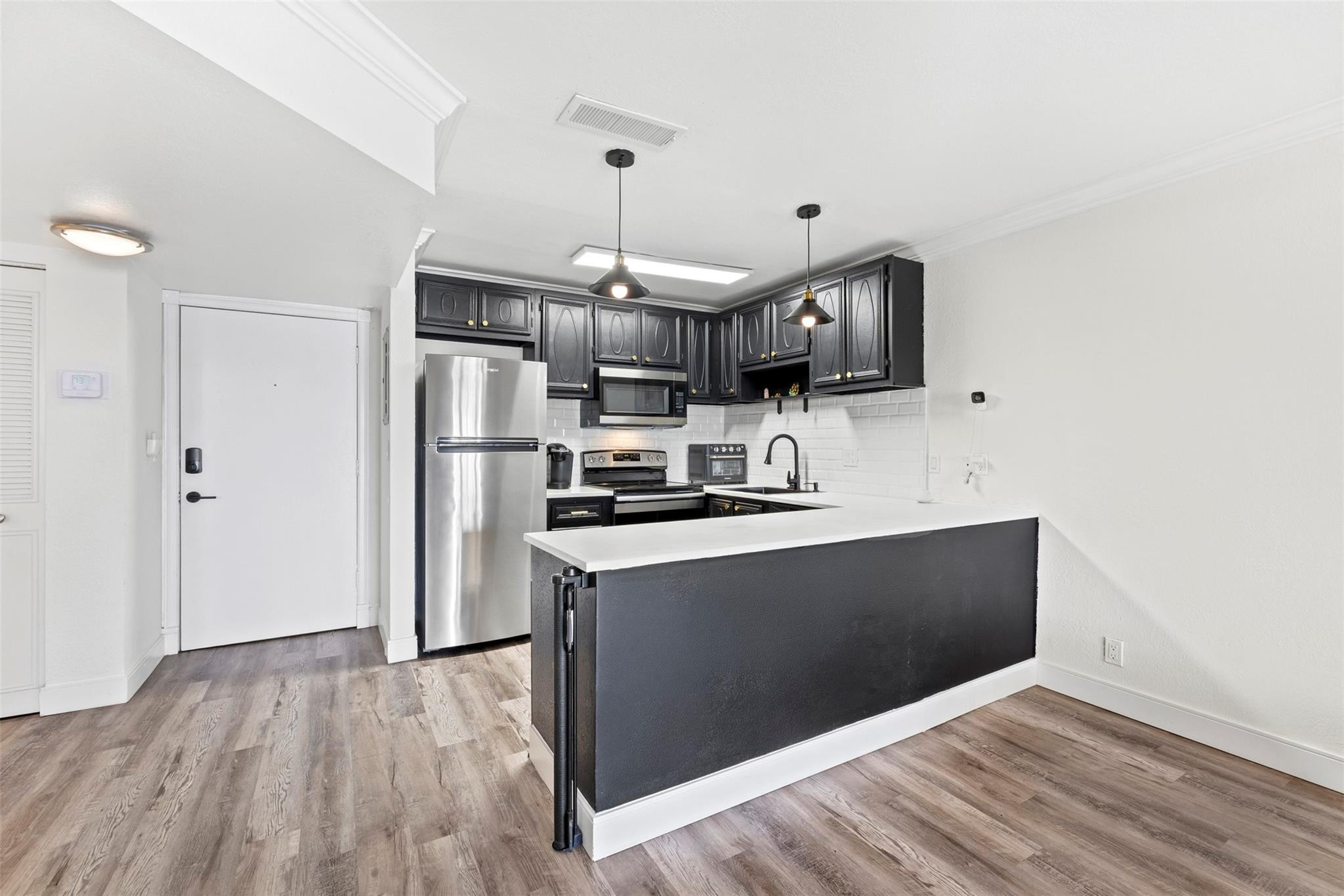 101 East McNab Road, Unit 219 Pompano Beach, FL 33060 - Photo 2 of 26 a kitchen with stainless steel appliances granite countertop a refrigerator a sink dishwasher a stove and white cabinets with wooden floor