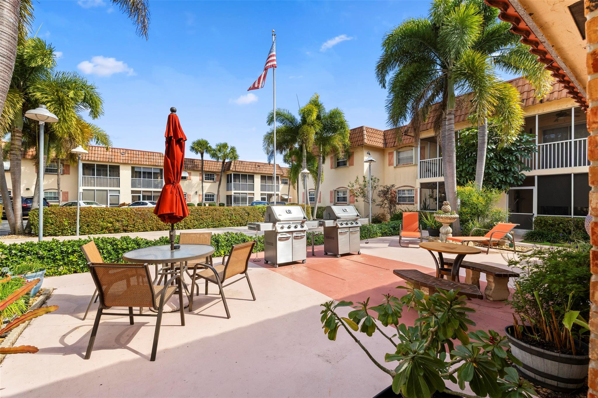 101 East McNab Road, Unit 219 Pompano Beach, FL 33060 - Photo 25 of 26 a view of a patio with dining table and chairs potted plants and palm trees