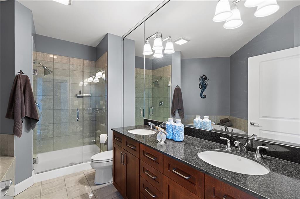 325 East Paces Ferry Road Northeast, Unit 1711 Atlanta, GA 30305 - Photo 11 of 29 a bathroom with a granite countertop sink a toilet a mirror a bathtub and shower