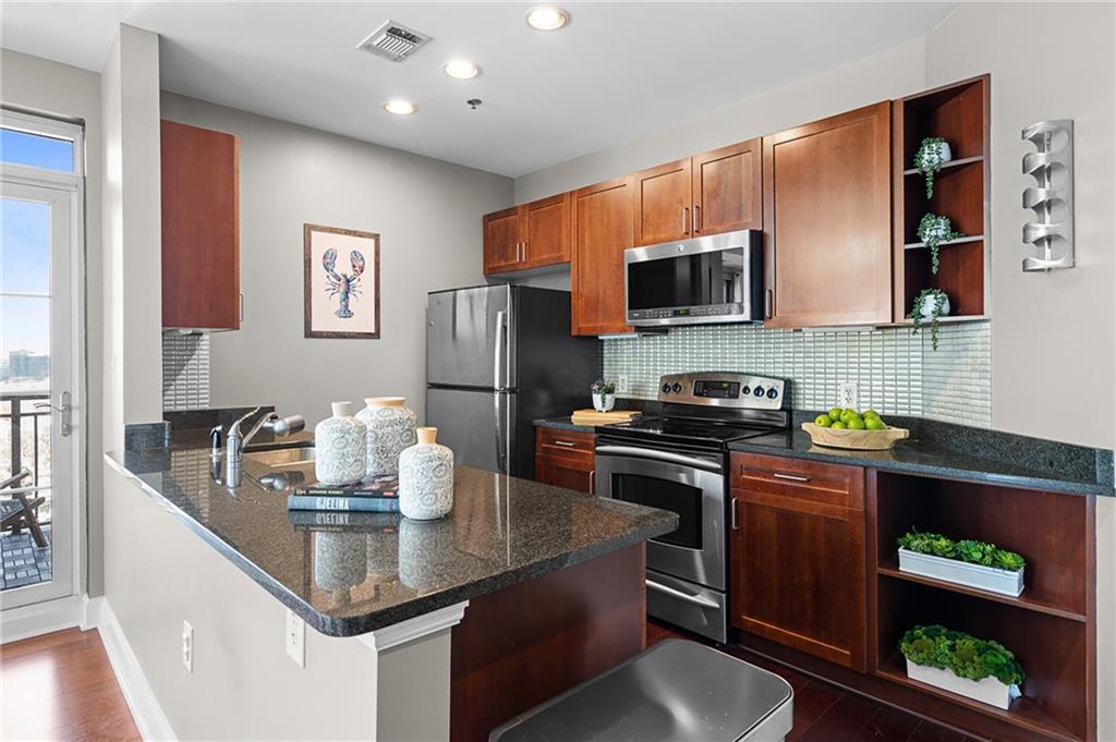 325 East Paces Ferry Road Northeast, Unit 1711 Atlanta, GA 30305 - Photo 6 of 29 a kitchen with stainless steel appliances granite countertop a refrigerator a stove a sink dishwasher and microwave with wooden floor