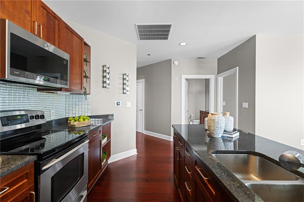 325 East Paces Ferry Road Northeast, Unit 1711 Atlanta, GA 30305 - Photo 7 of 29 a kitchen with stainless steel appliances a stove a sink a microwave and wooden cabinets