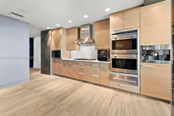 a kitchen with stainless steel appliances kitchen island granite countertop a stove a refrigerator and a microwave oven with wooden floor