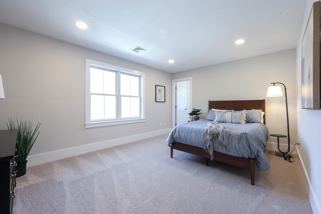 55 Thomas Mann Circle, Unit 32 Norfolk, MA 02056 - Photo 17 of 31 a spacious bedroom with a bed lamp and a potted plant