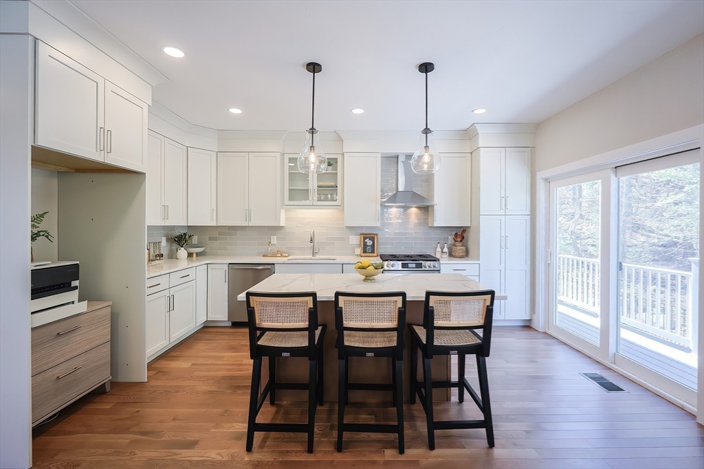 55 Thomas Mann Circle, Unit 32 Norfolk, MA 02056 - Photo 26 of 31 a kitchen with stainless steel appliances granite countertop a stove a refrigerator a kitchen island a dining table and chairs with wooden floor