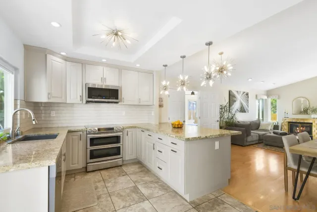 a kitchen with granite countertop white cabinets stainless steel appliances and a sink