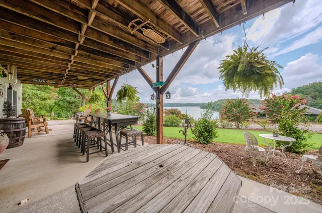 a view of a patio with table and chairs under an umbrella with a large tree