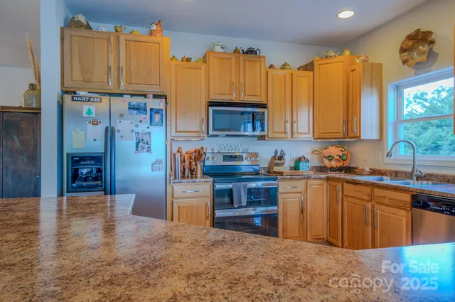 a kitchen with stainless steel appliances granite countertop a stove a sink dishwasher and a refrigerator