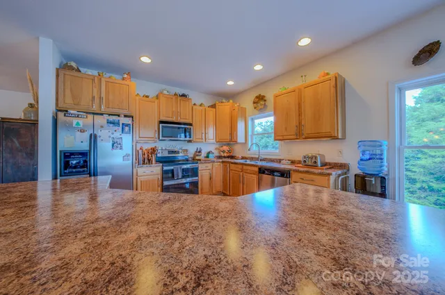 a kitchen with stainless steel appliances granite countertop a refrigerator a sink and a stove