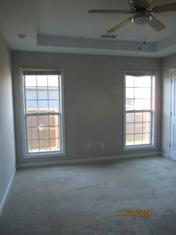 an empty room with windows and fan