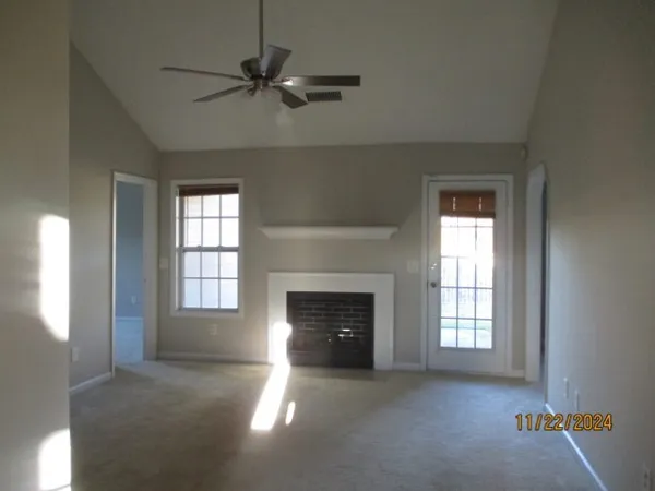 an empty room with windows and fireplace