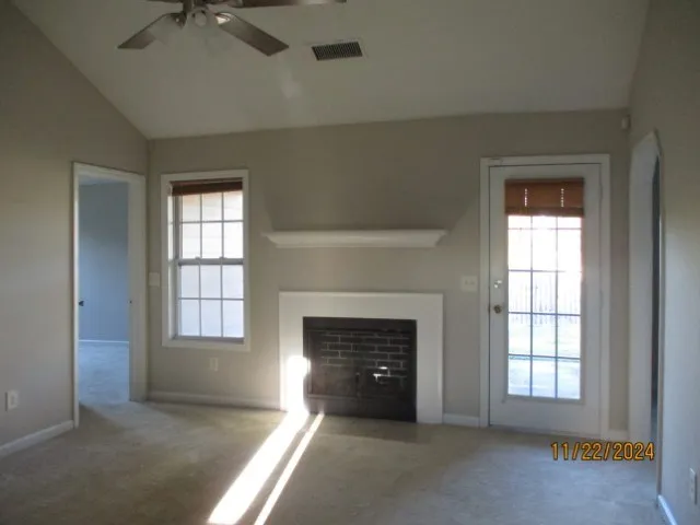 an empty room with windows and fireplace