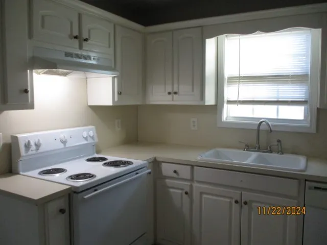 a kitchen with a sink a stove cabinets and a window