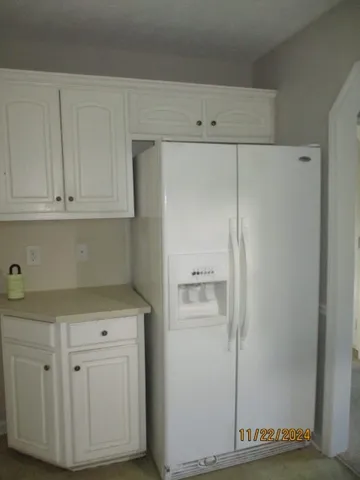 a kitchen with white cabinets and a refrigerator
