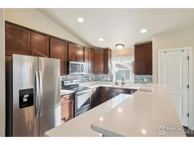 a kitchen with stainless steel appliances granite countertop a refrigerator a sink a stove and oven