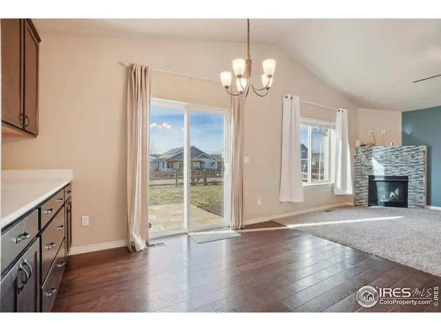 a view of an empty room with wooden floor fireplace and a window