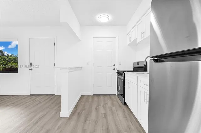 a view of a kitchen with white cabinets and wooden floor