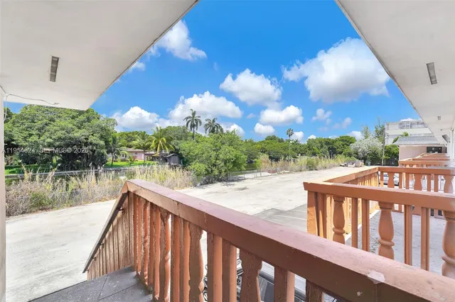 a balcony with wooden floor and yard in the back
