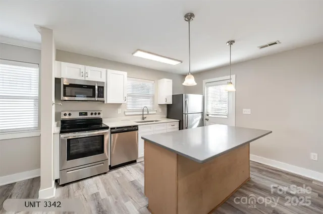 a kitchen with stainless steel appliances granite countertop a stove a microwave a sink a refrigerator and white cabinets