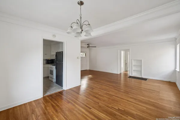 a view of an empty room with window and wooden floor