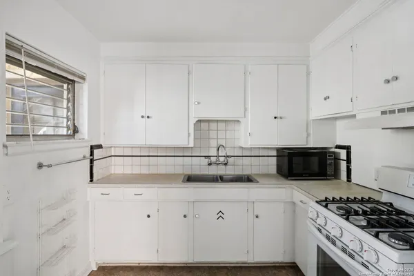 a kitchen with granite countertop white cabinets and a stove
