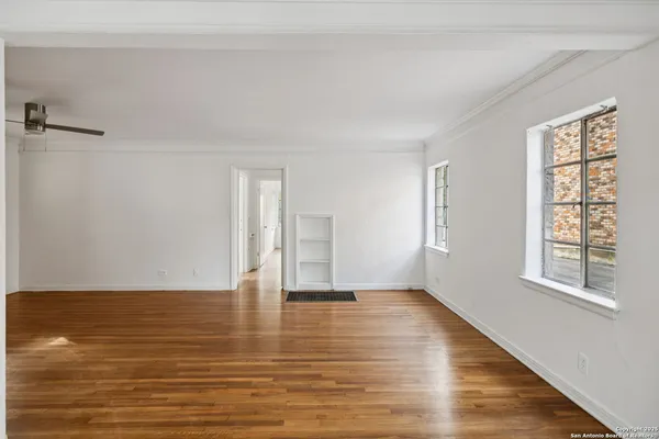 a view of an empty room with wooden floor and a window