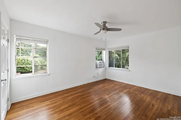 a view of empty room with wooden floor and fan
